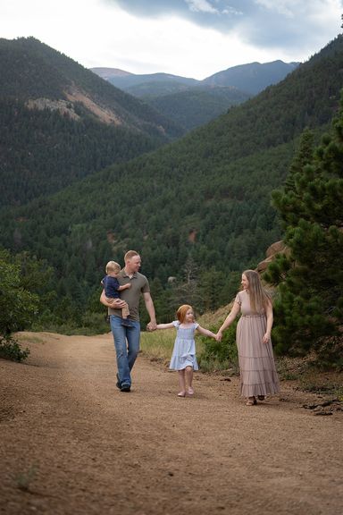 Family of four walking hand in hand along a mountain trail in Colorado