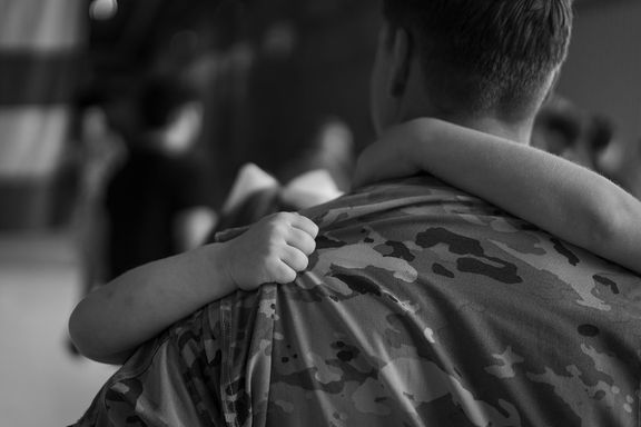 Child holding tightly to a service member during a homecoming reunion