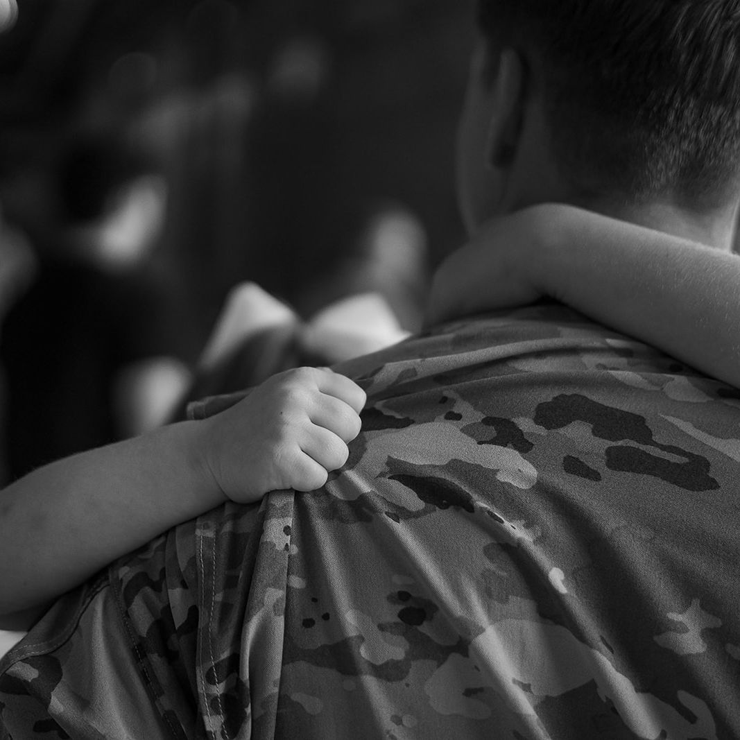 Child holding tightly to a service member during an emotional military homecoming reunion in Colorado Springs
