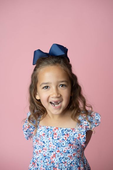 Smiling young girl with a blue bow during a colorful studio personality portrait