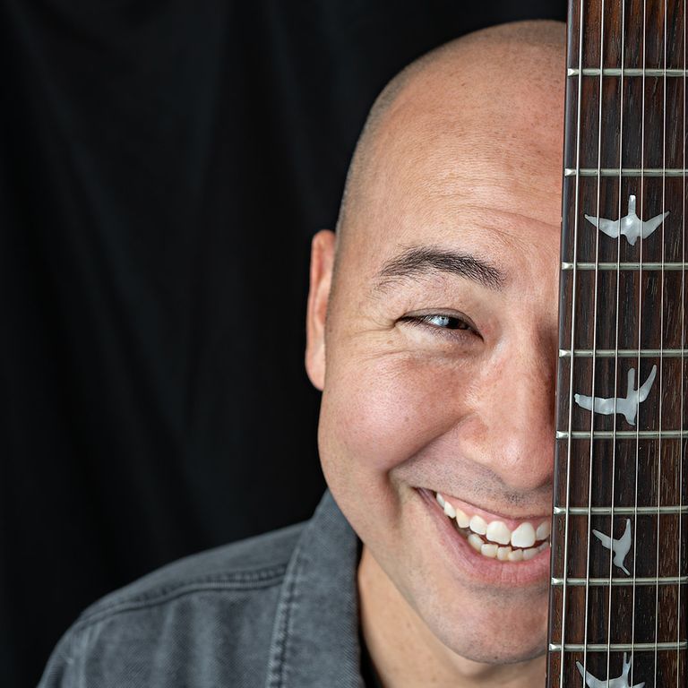 Smiling musician with guitar during a creative professional headshot session