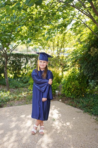  Kindergarten graduate posing outdoors in a blue cap and gown