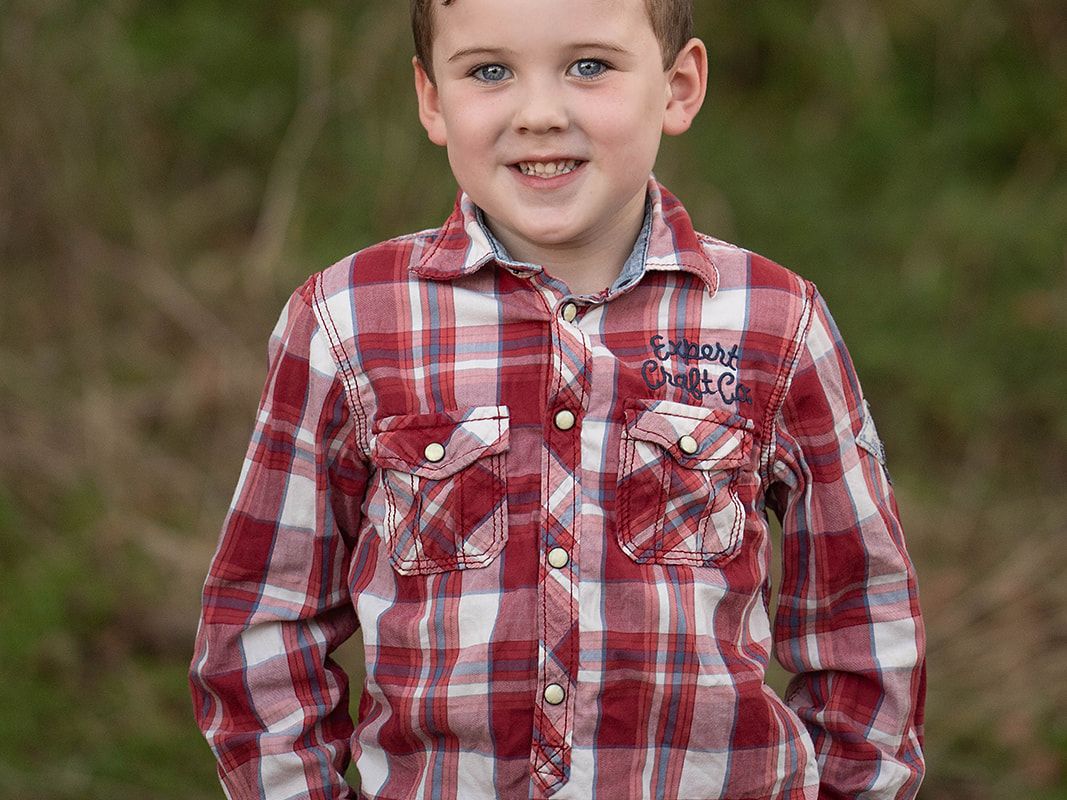 Young boy smiling outdoors during a child personality portrait session