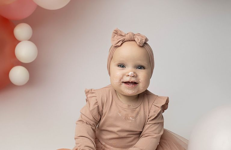 Baby girl smiling during a first birthday milestone photography session in the studio