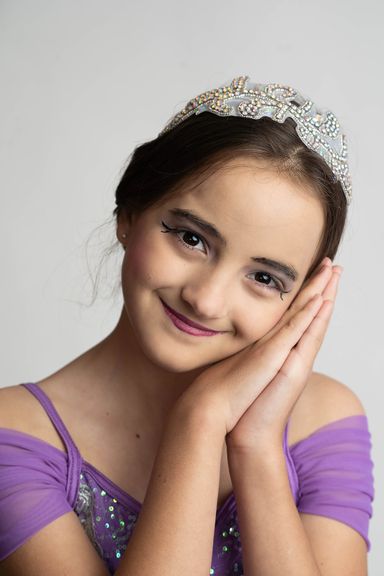 Young dancer in a purple costume posing for a studio dance portrait