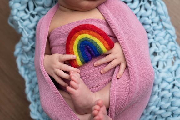 Newborn baby wrapped in pink with a rainbow detail