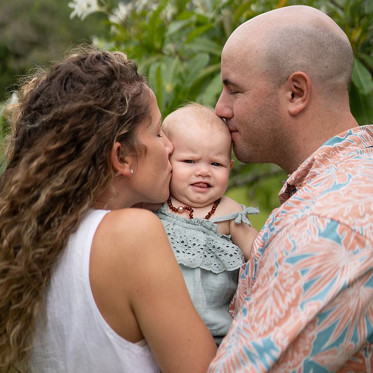 Parents kissing their baby girl during an outdoor family photography session
