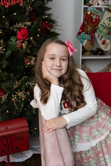 Young girl posing for an indoor Christmas portrait with festive holiday decorations in Colorado Springs.