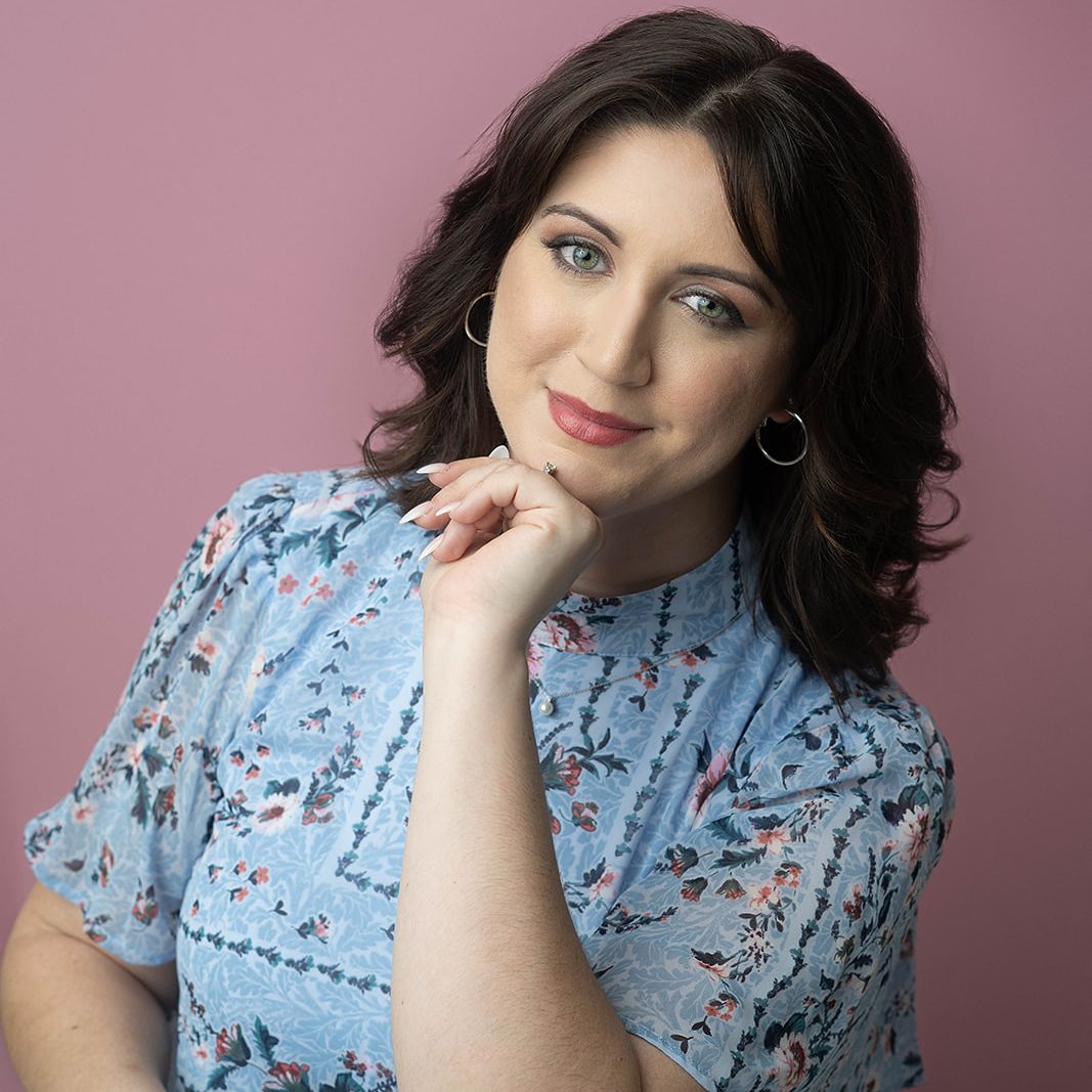 Professional headshot of a woman photographed against a pink studio backdrop in Colorado Springs