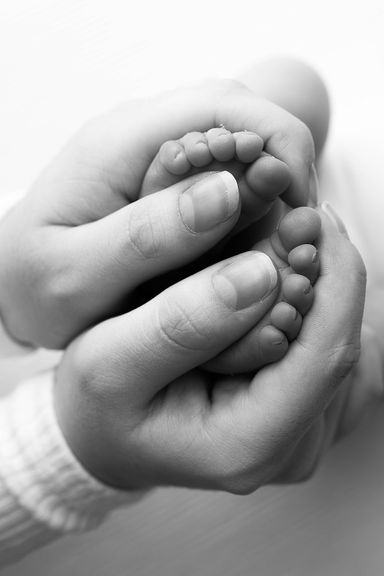 
Close-up of newborn baby's tiny feet held in a parent's hands