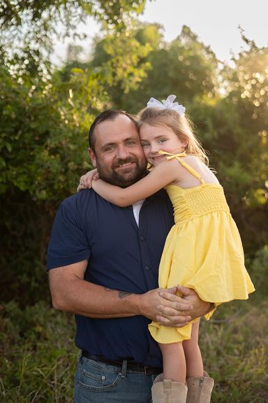 Father holding his young daughter during a warm outdoor family portrait session