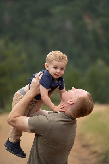 Father lifting his young son during a playful outdoor family photography session
