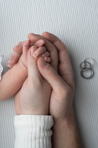 Close-up of a newborn baby's tiny hand holding an adult's finger