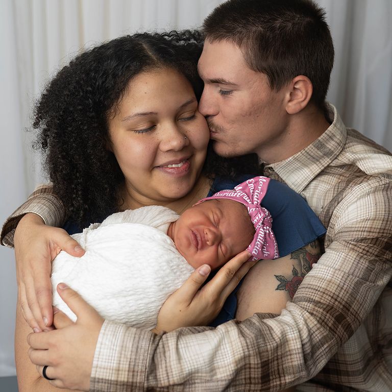 Parents cuddling their newborn baby during a relaxed studio newborn photography session