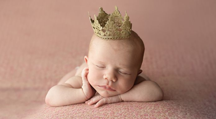 Sleeping newborn baby wearing a delicate crown during a posed studio session