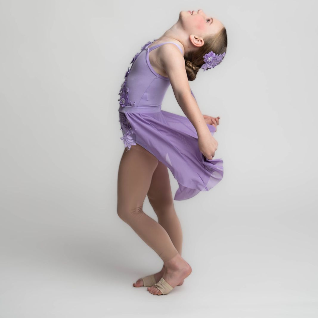 Young dancer in a purple costume posing during a studio dance photography session
