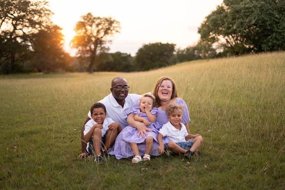 Family laughing together in a sunlit field during a Colorado Springs family session