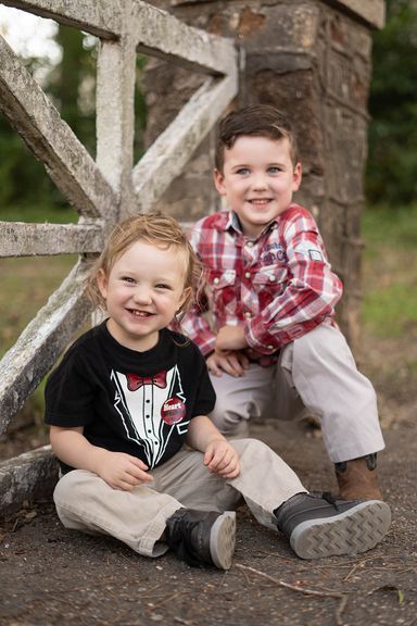 Two young brothers smiling together during an outdoor childhood portrait session