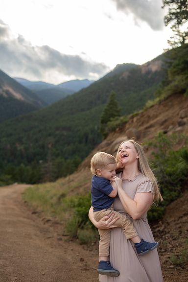Mother laughing while holding her young son during a Colorado mountain family session
