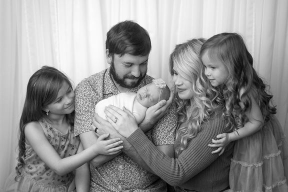 black and white image of family holding baby 