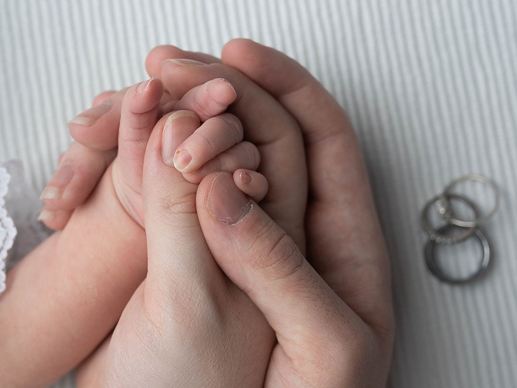 Close-up of newborn baby's tiny hands resting in a parent's hands